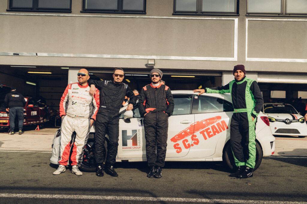 Equipaggio di piloti in tuta accanto alla vettura di una gara Endurance 4h